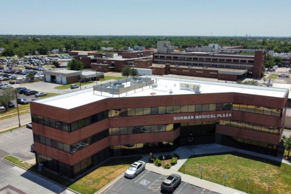 Aerial view of Norman Medical Plaza featuring a modern flat roof, surrounded by parking and other medical facilities, highlighting commercial roofing solutions relevant to Oklahoma's climate.